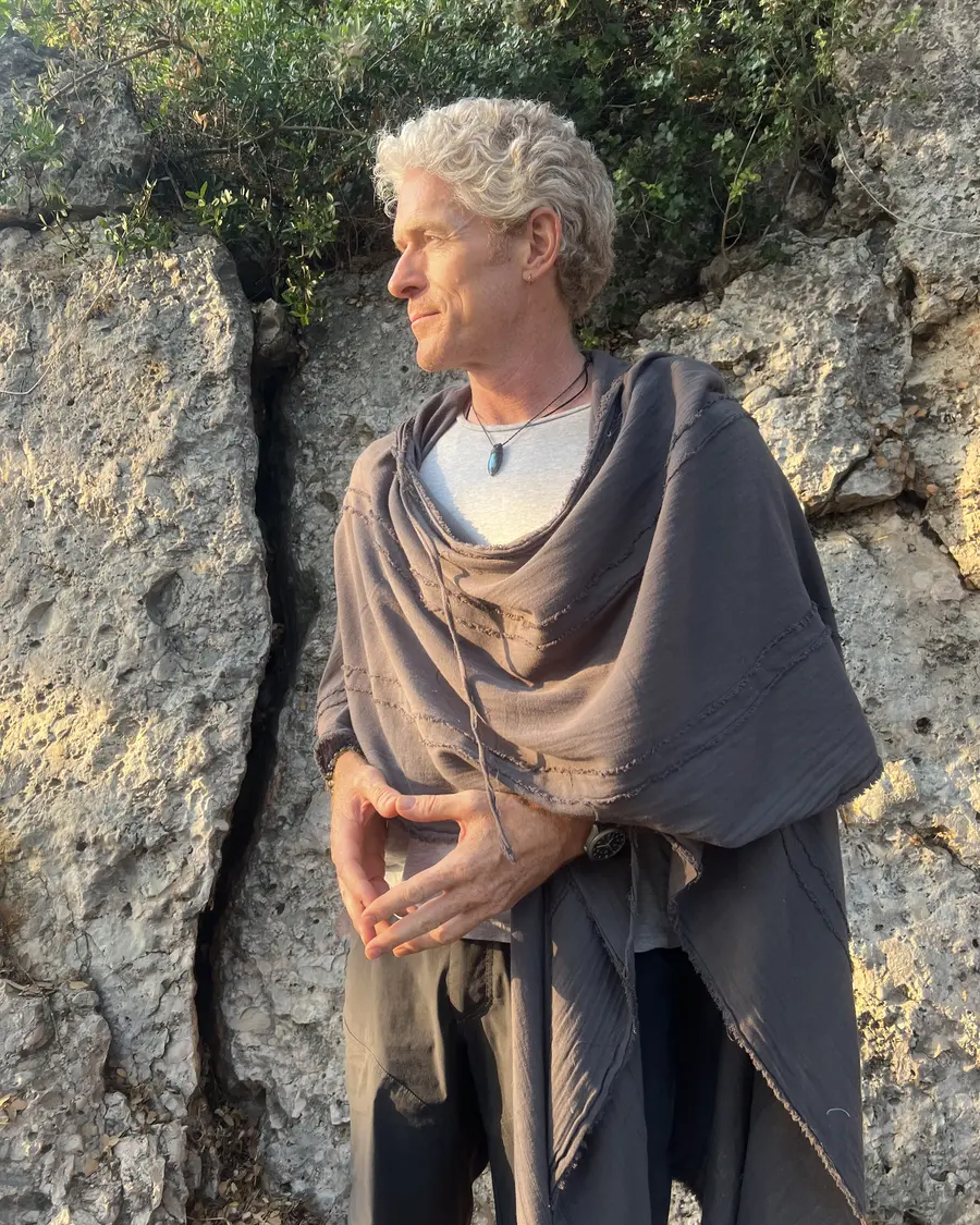 Phil outdoors wrapped in a cloak, looking out over the landscape