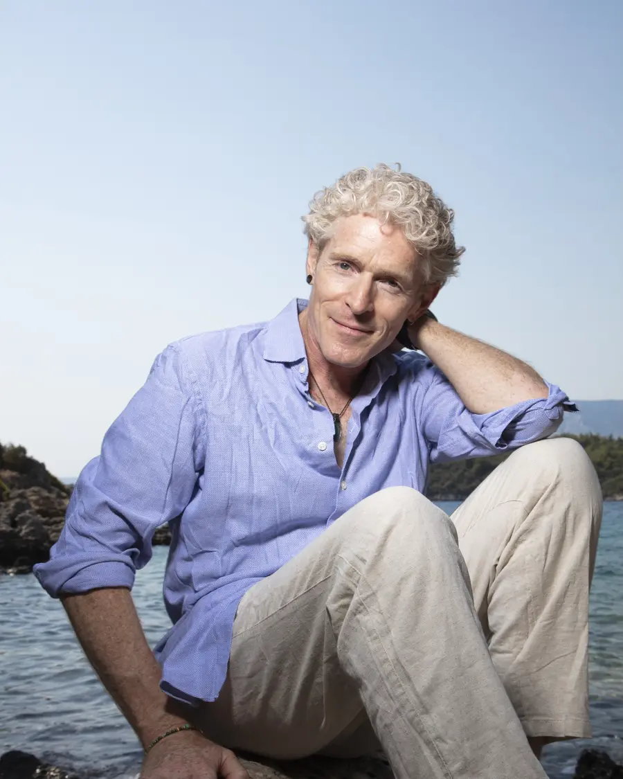 Phil Duval in a blue shirt by the sea, smiling
