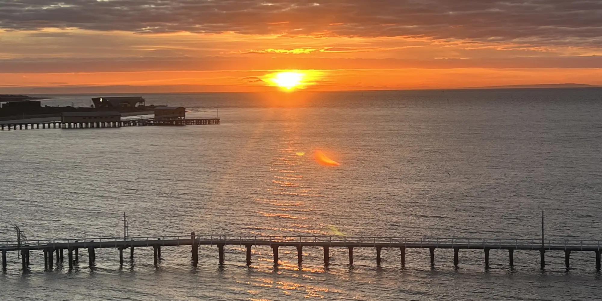 A timber jetty reaching out over calm water at dawn