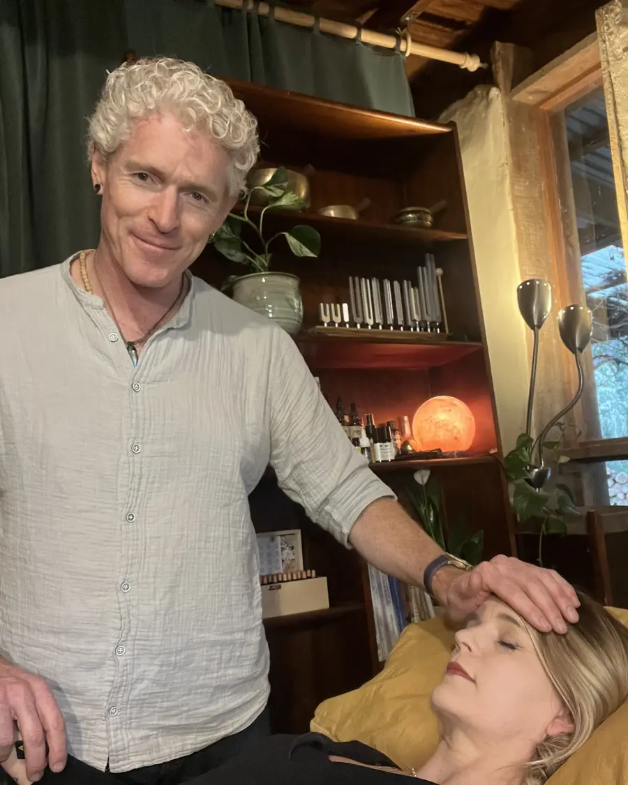 Phil resting his hands lightly on a client's forehead during a kinesiology session